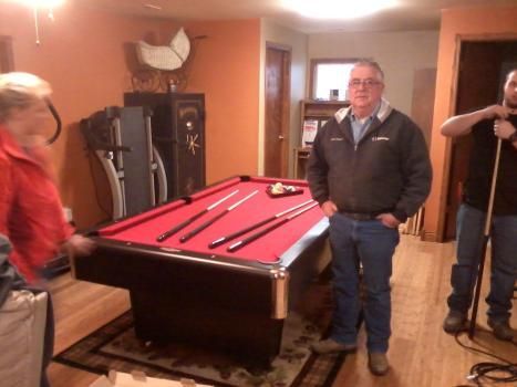 A group of people standing around a pool table