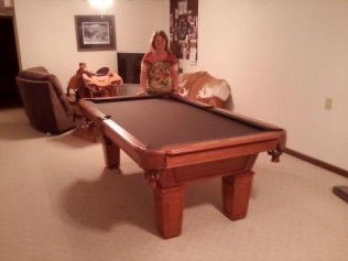 A woman is standing next to a pool table in a living room.