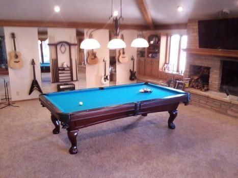 A pool table in a room with guitars on the wall