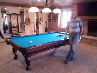 A man is standing next to a pool table in a living room.
