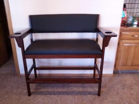 A wooden chair with a black seat and arm rests