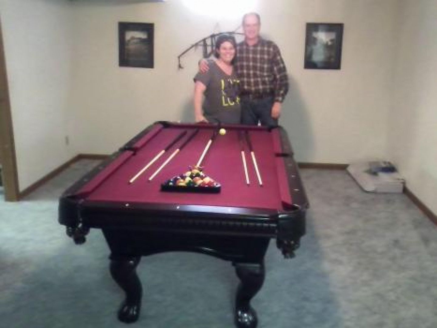 A man and a woman pose in front of a pool table