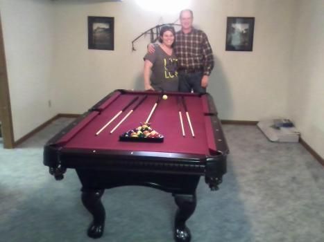 A man and a woman pose in front of a pool table