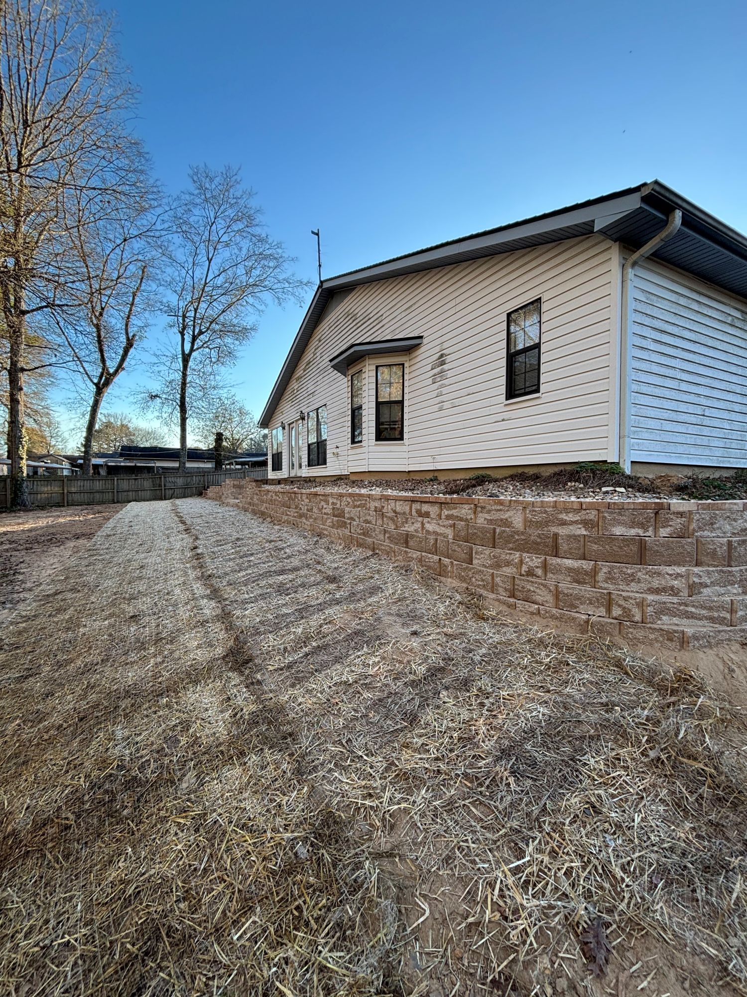 A house with white siding and a brown retaining wall in front.