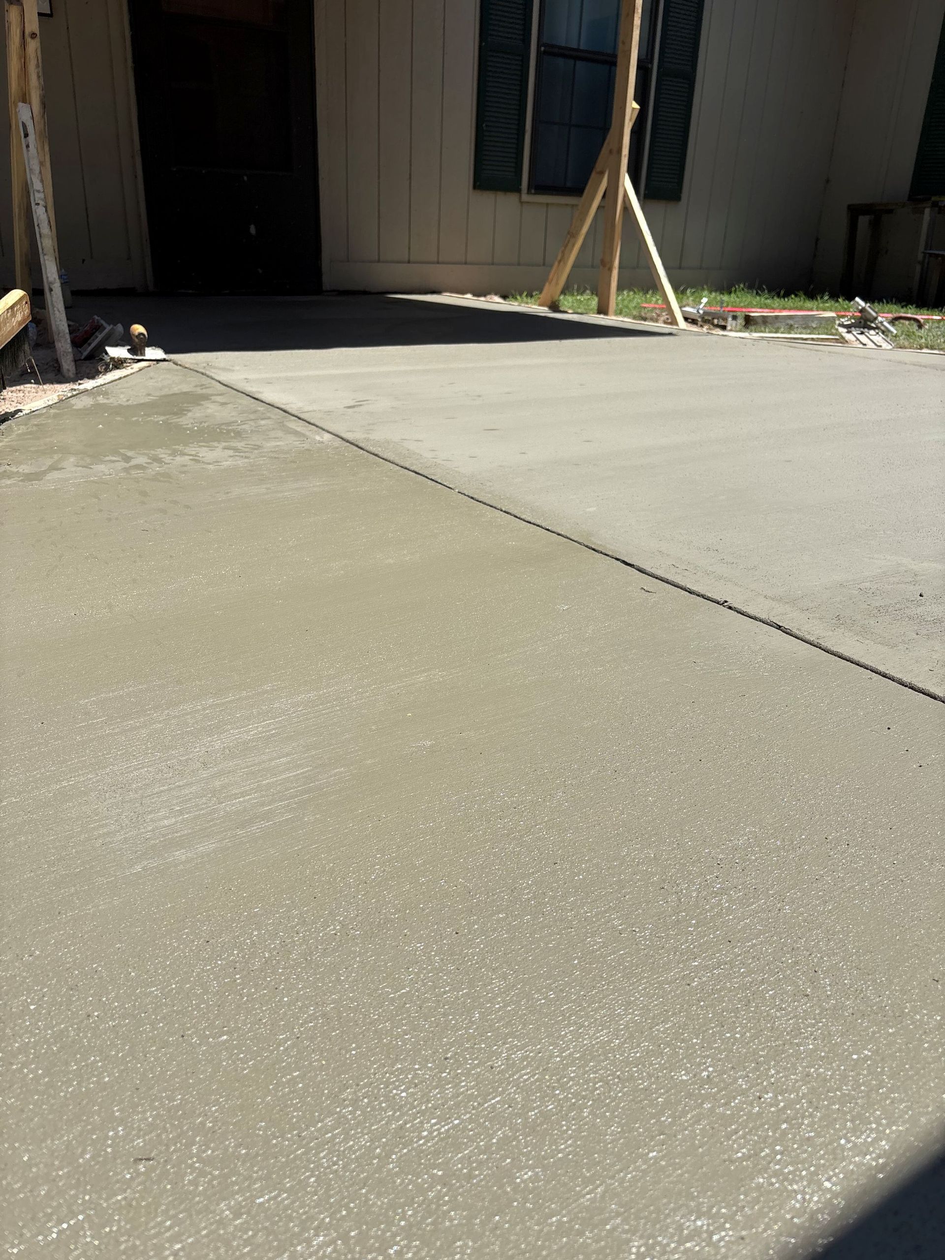 Freshly poured concrete driveway in front of a house.