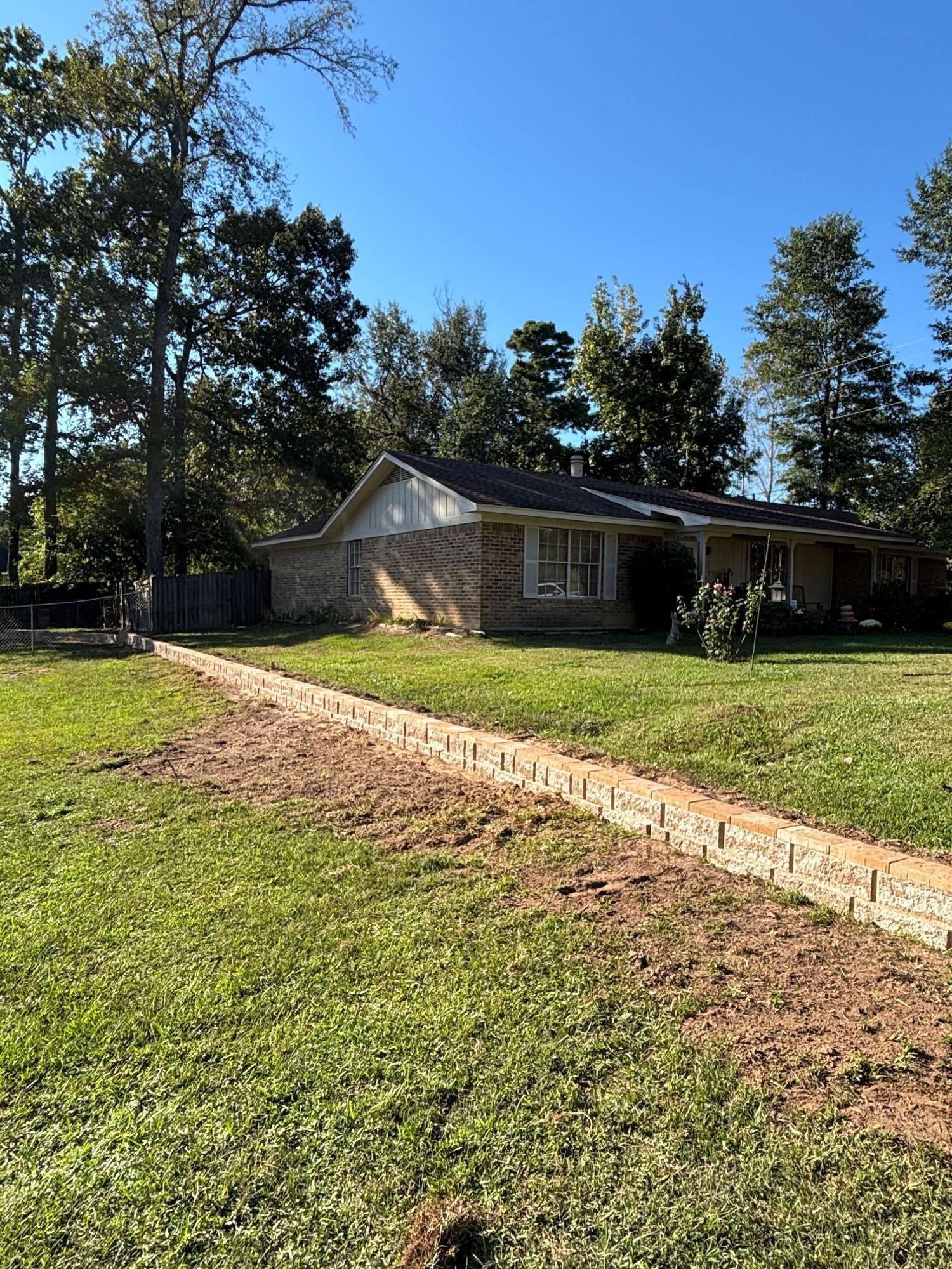Brick pathway leads to a single-story house with a brick facade on a sunny day.