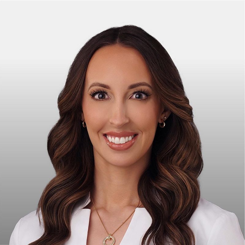 Dr. Whitney Call, a woman in a white lab coat is smiling for the camera.
