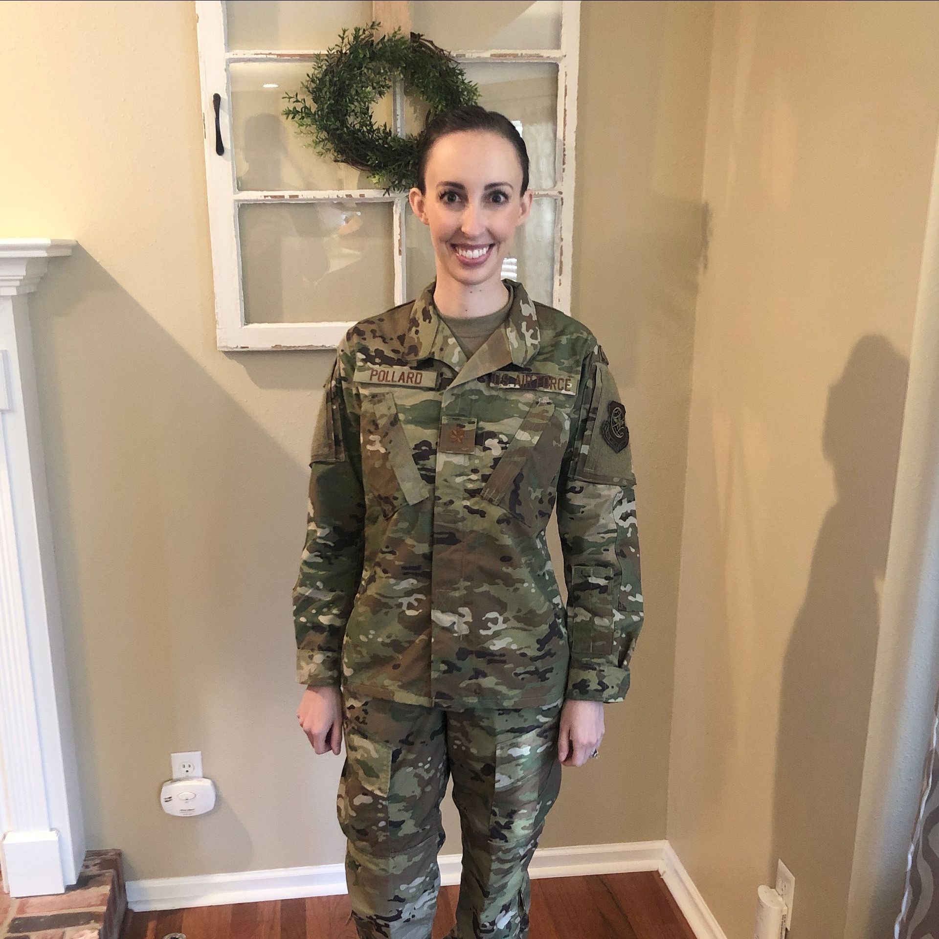 A woman in a military uniform is standing in a living room