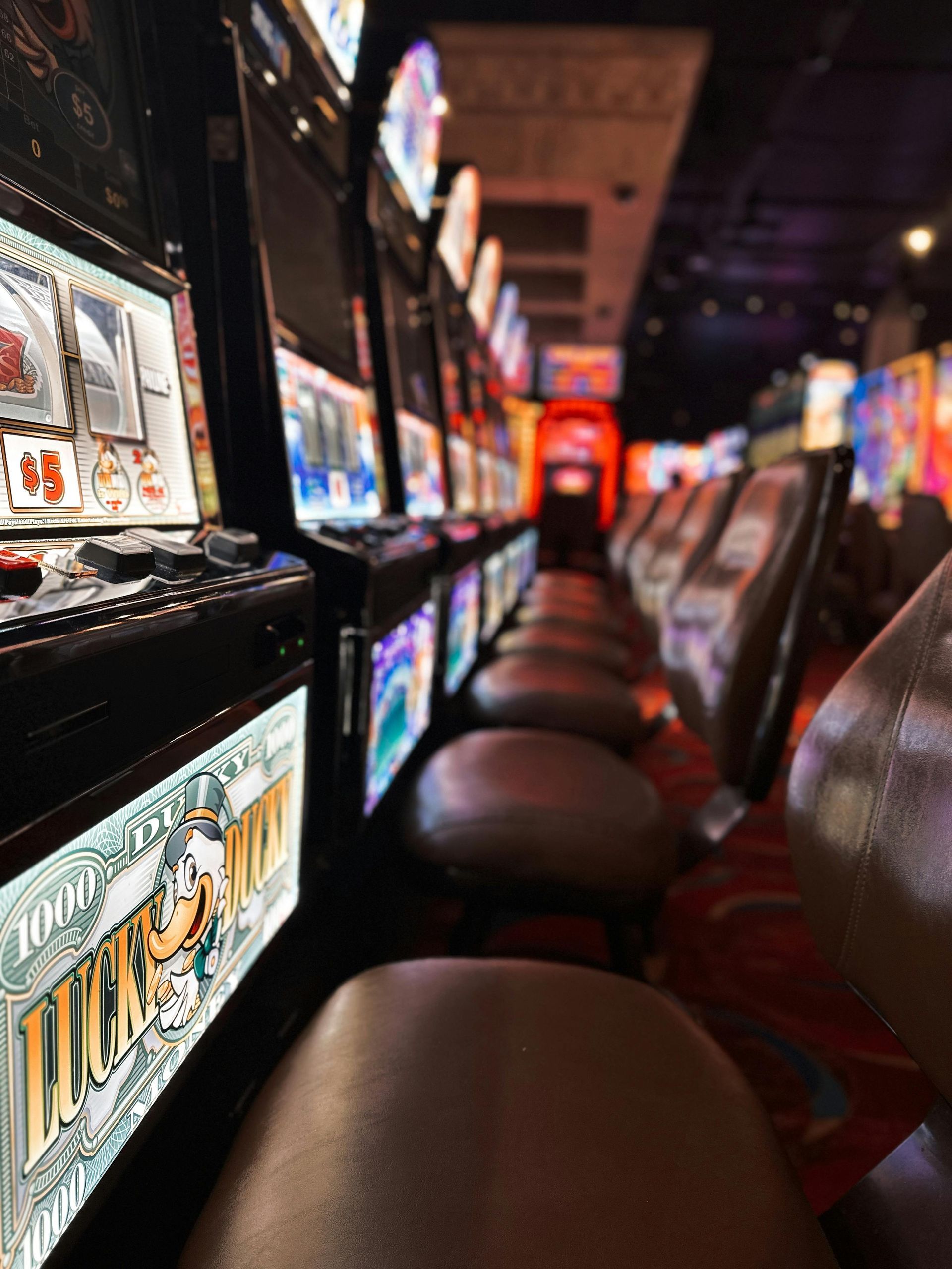 A row of slot machines are lined up in a gambling room.