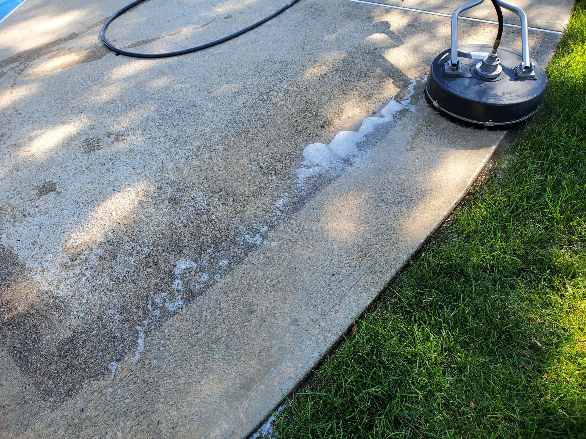 A concrete surface is being cleaned with a pressure washer.