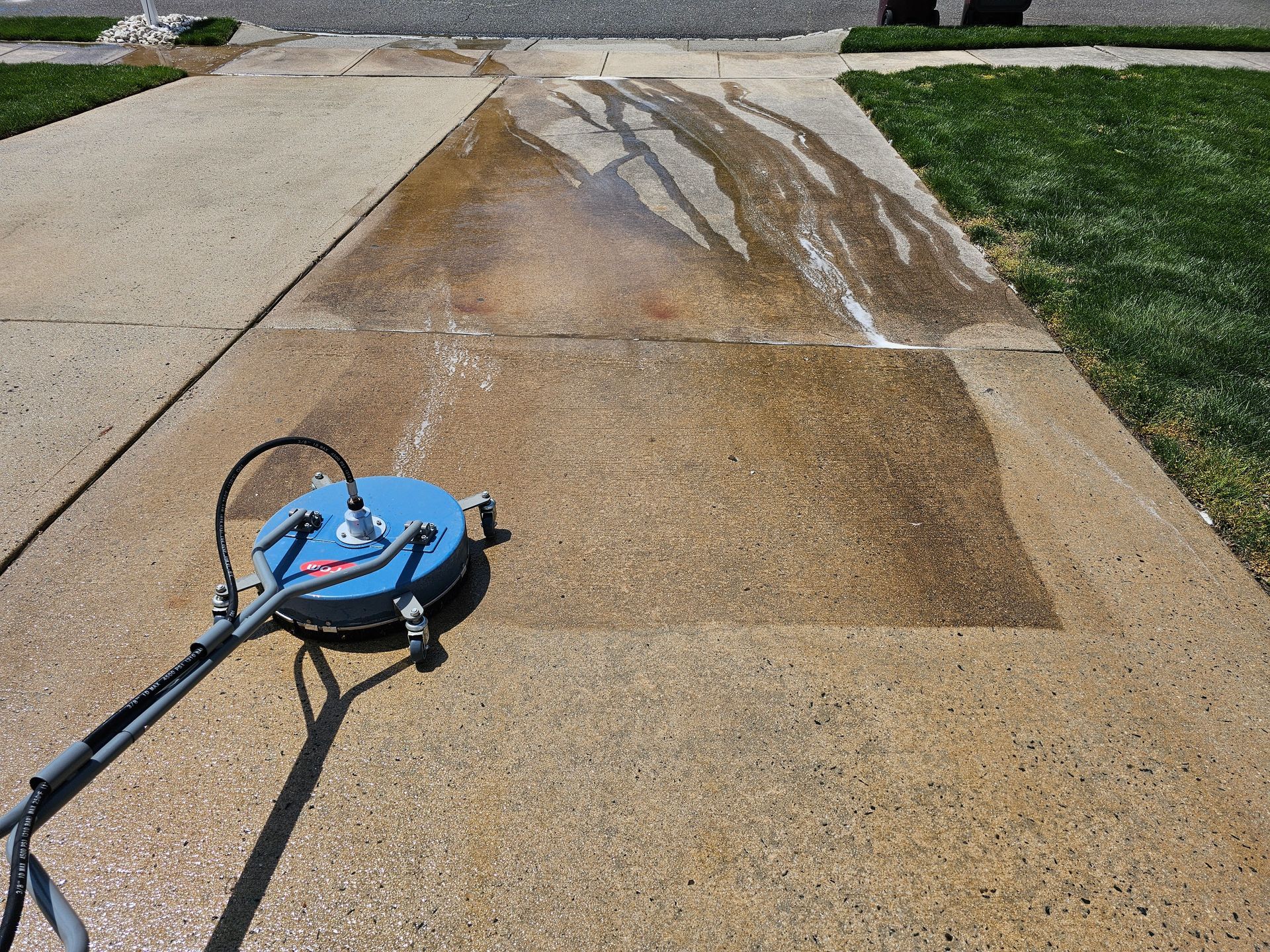 A concrete driveway is being cleaned with a machine