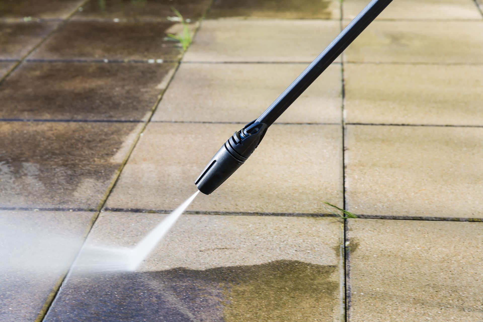 A person is using a high pressure washer to clean a tiled floor.