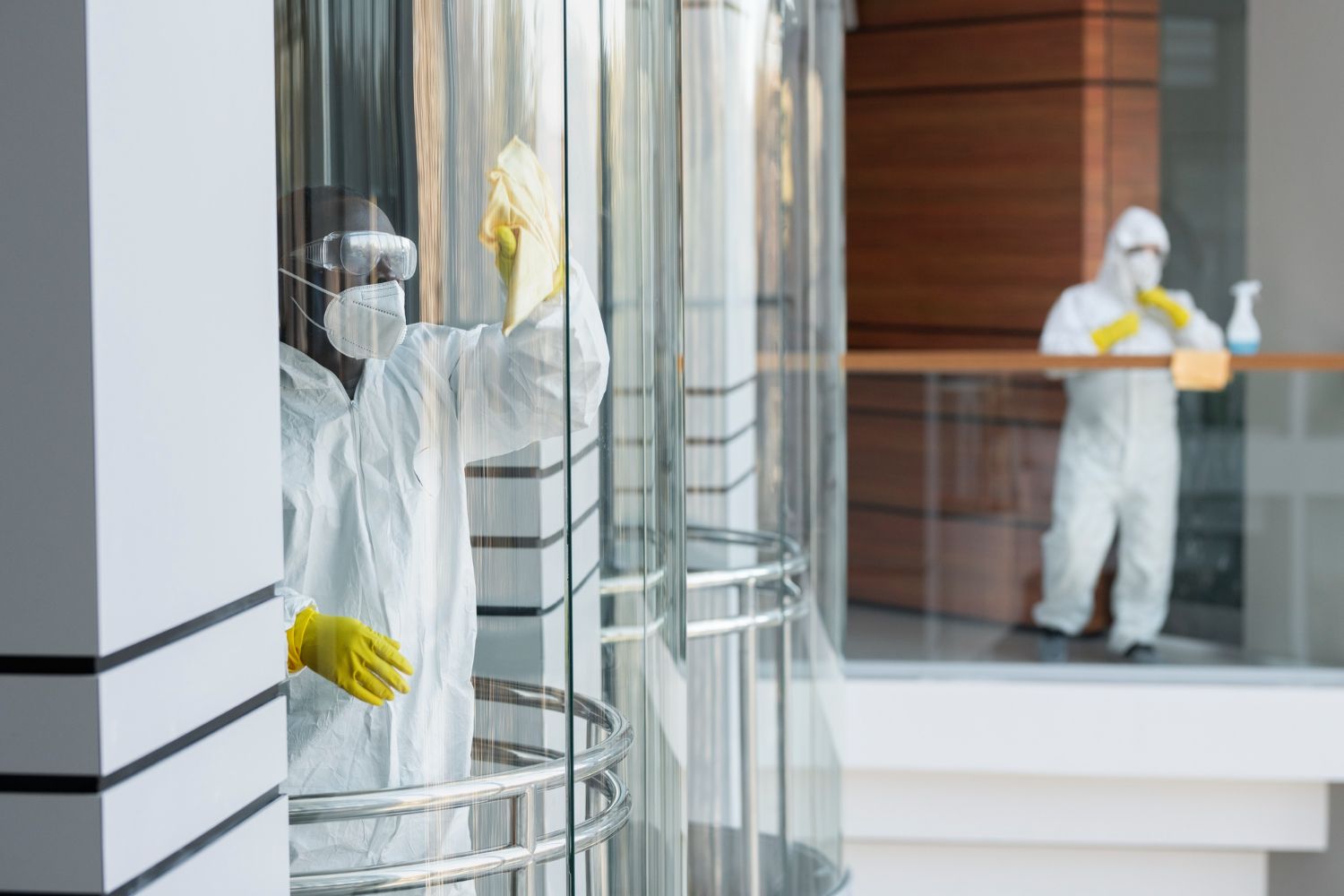 A man in a protective suit is cleaning an elevator door.