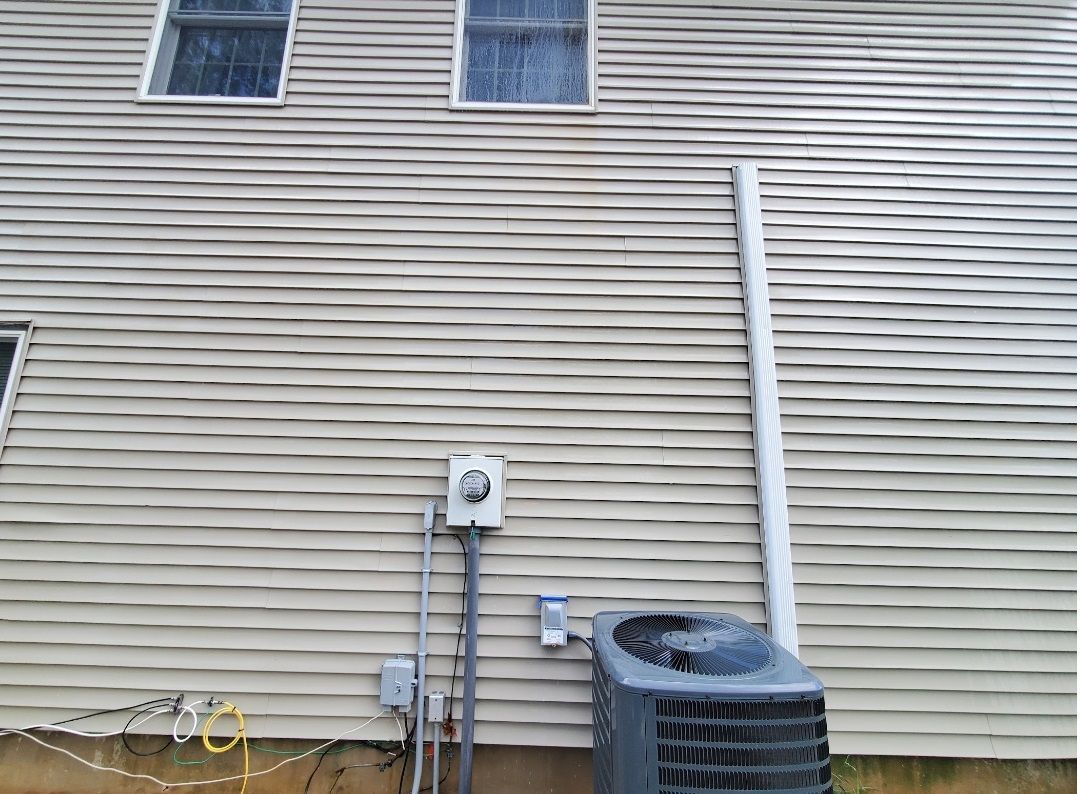 A house with a gray air conditioner on the side of it.