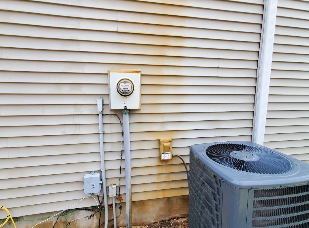 An air conditioner is sitting on the side of a house.