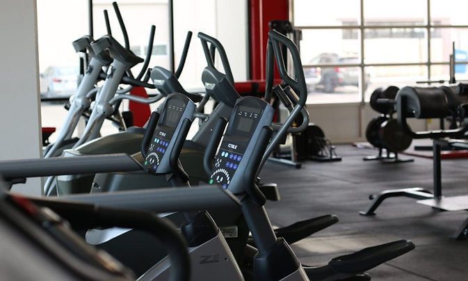 A row of ellipticals are lined up in a gym.