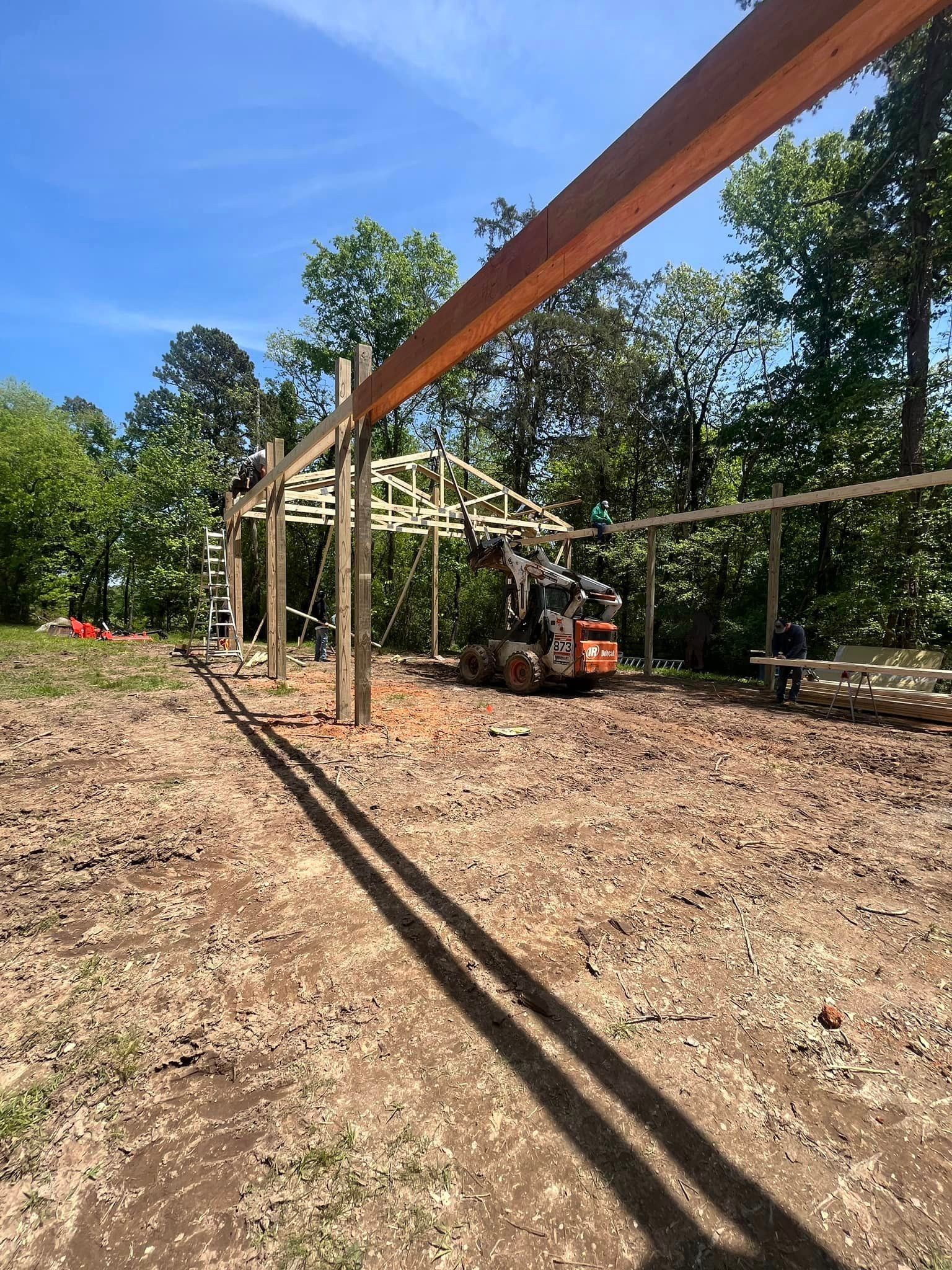 A large wooden structure is being built in the middle of a dirt field.