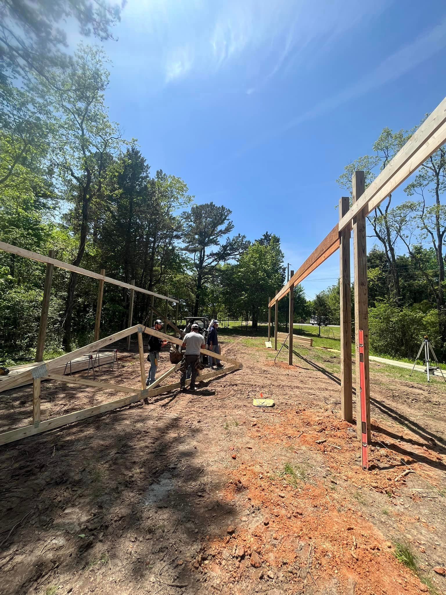 A group of people are working on a wooden fence in a dirt field.