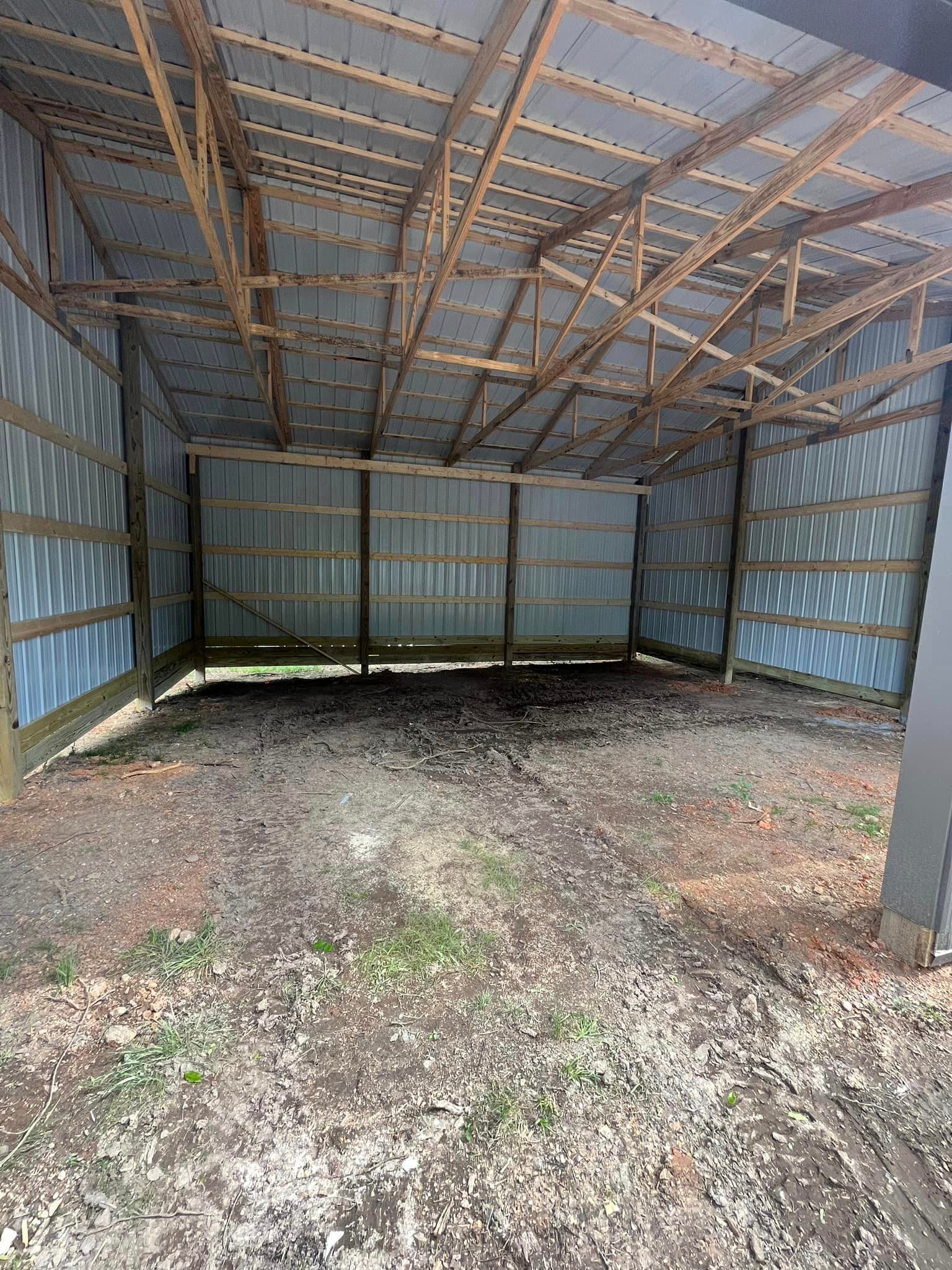 The inside of a barn with a metal roof and wooden beams.