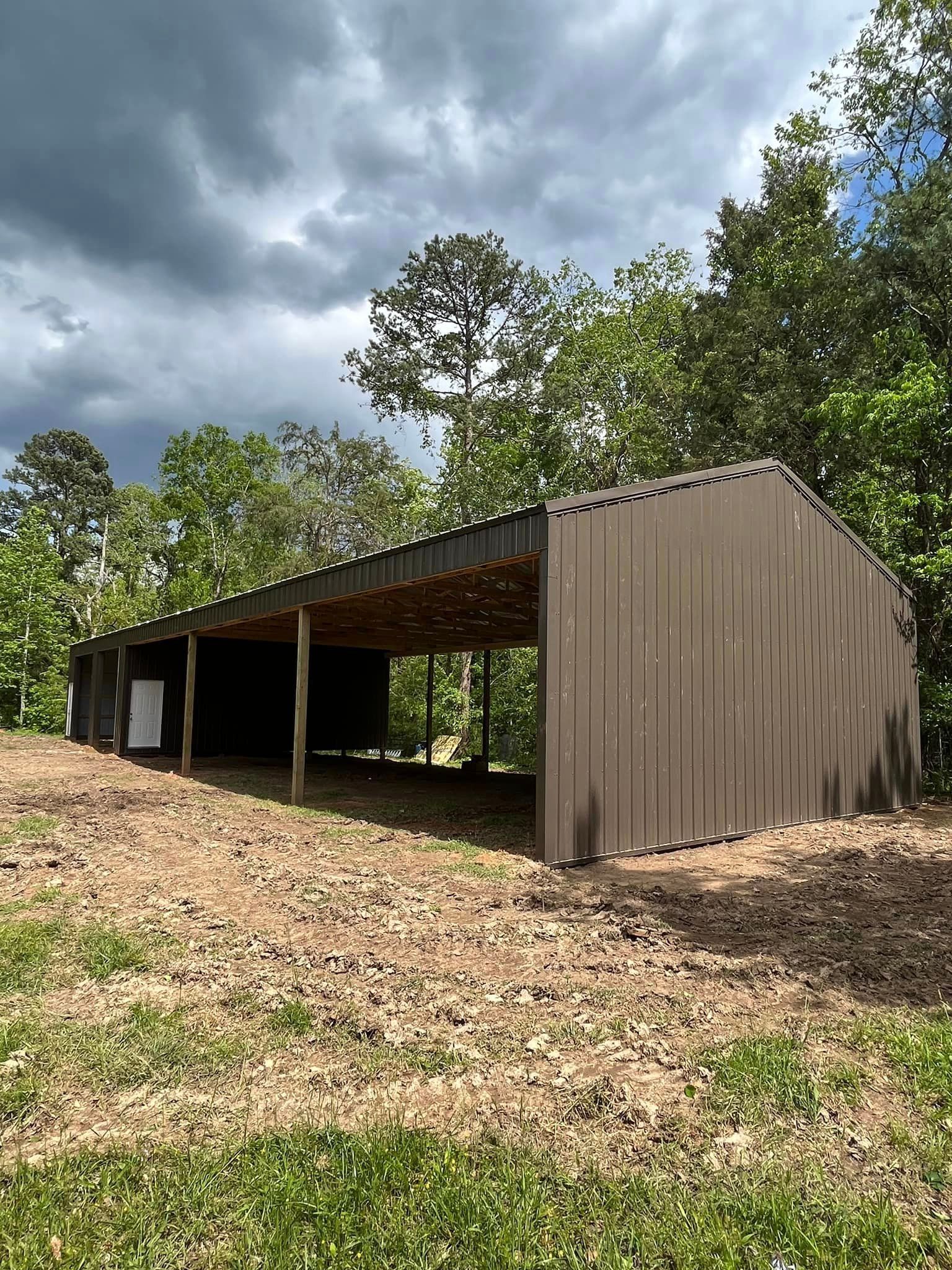 A large barn is sitting on top of a hill in the middle of a field.