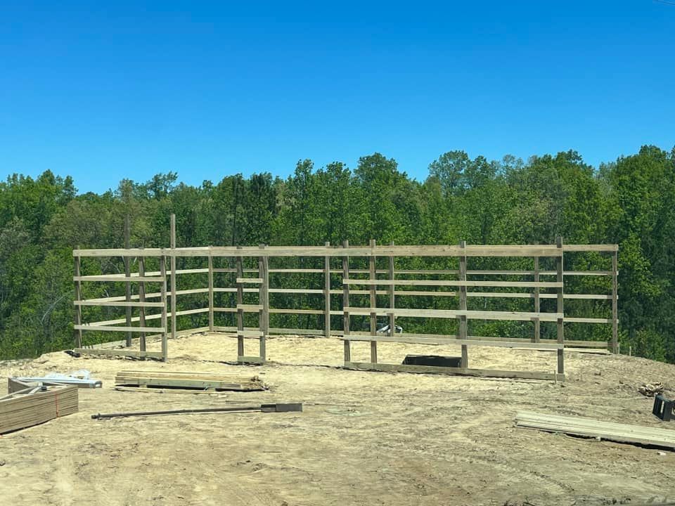 A large wooden structure is being built in the middle of a dirt field.
