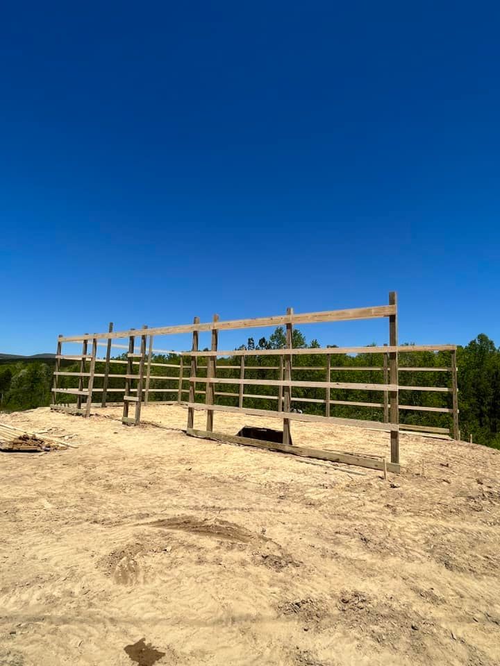 A wooden fence is sitting in the middle of a dirt field.