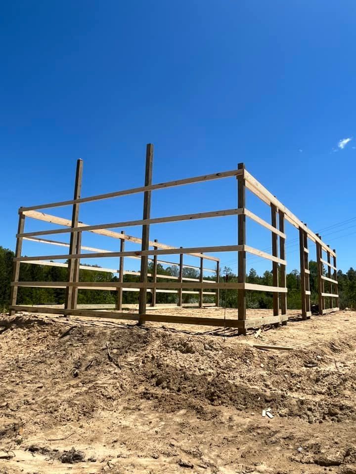 A wooden fence is being built in the middle of a dirt field