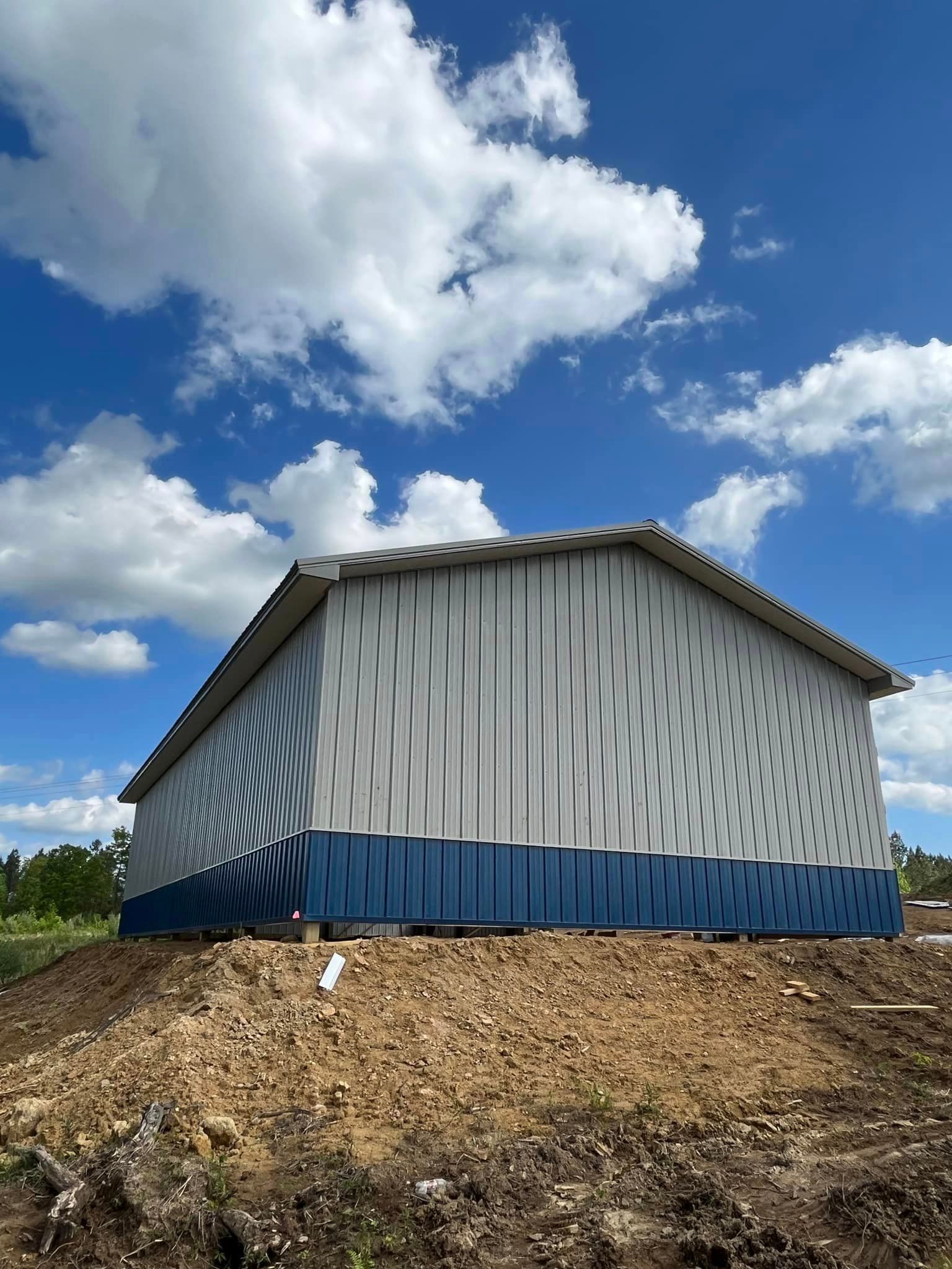 A white and blue building is sitting on top of a dirt hill.