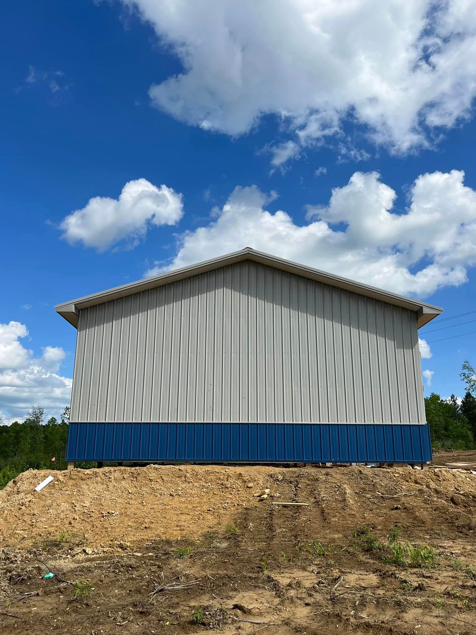 A white and blue building is sitting on top of a dirt hill.
