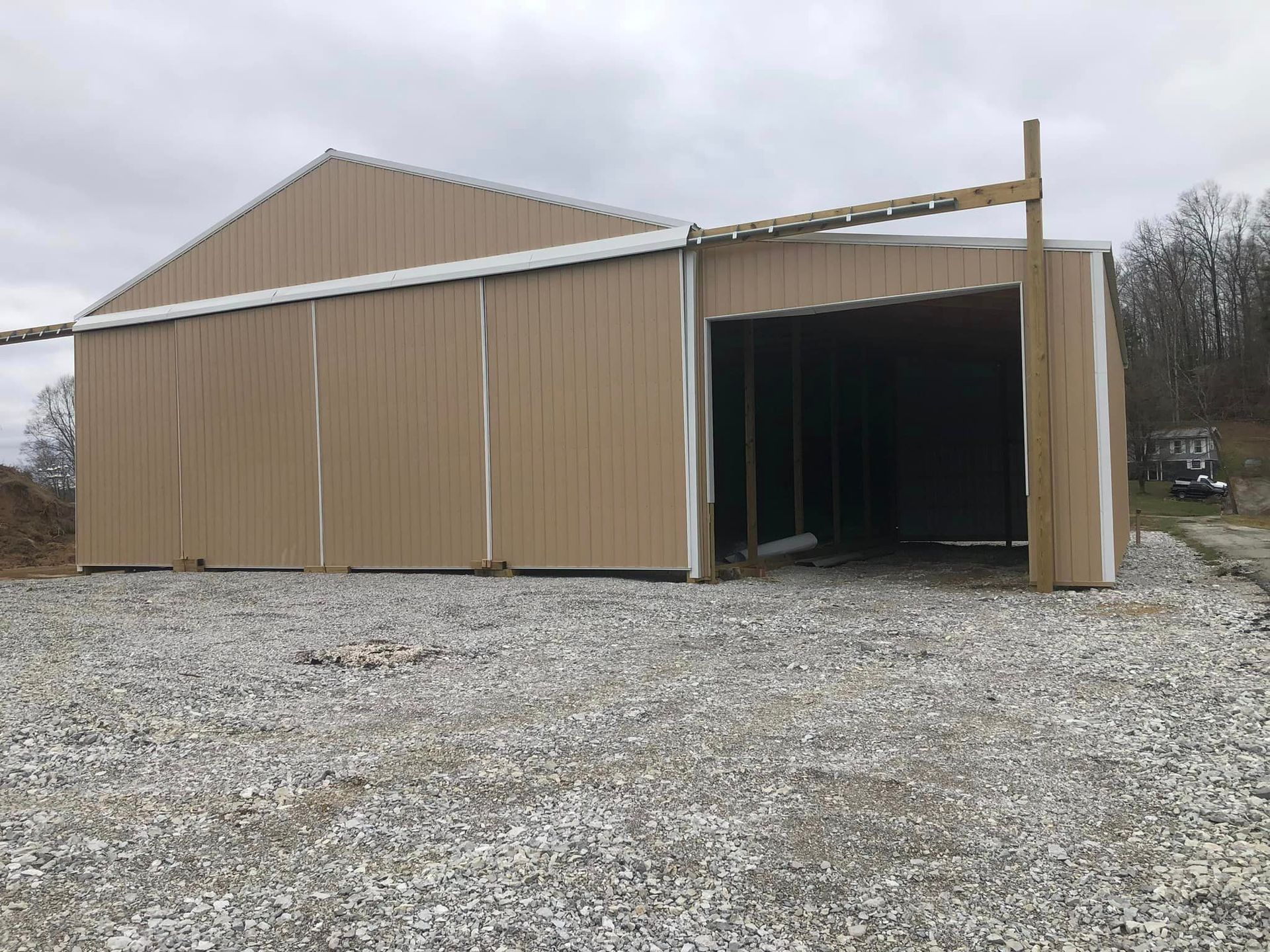 A large barn is sitting on top of a gravel lot.