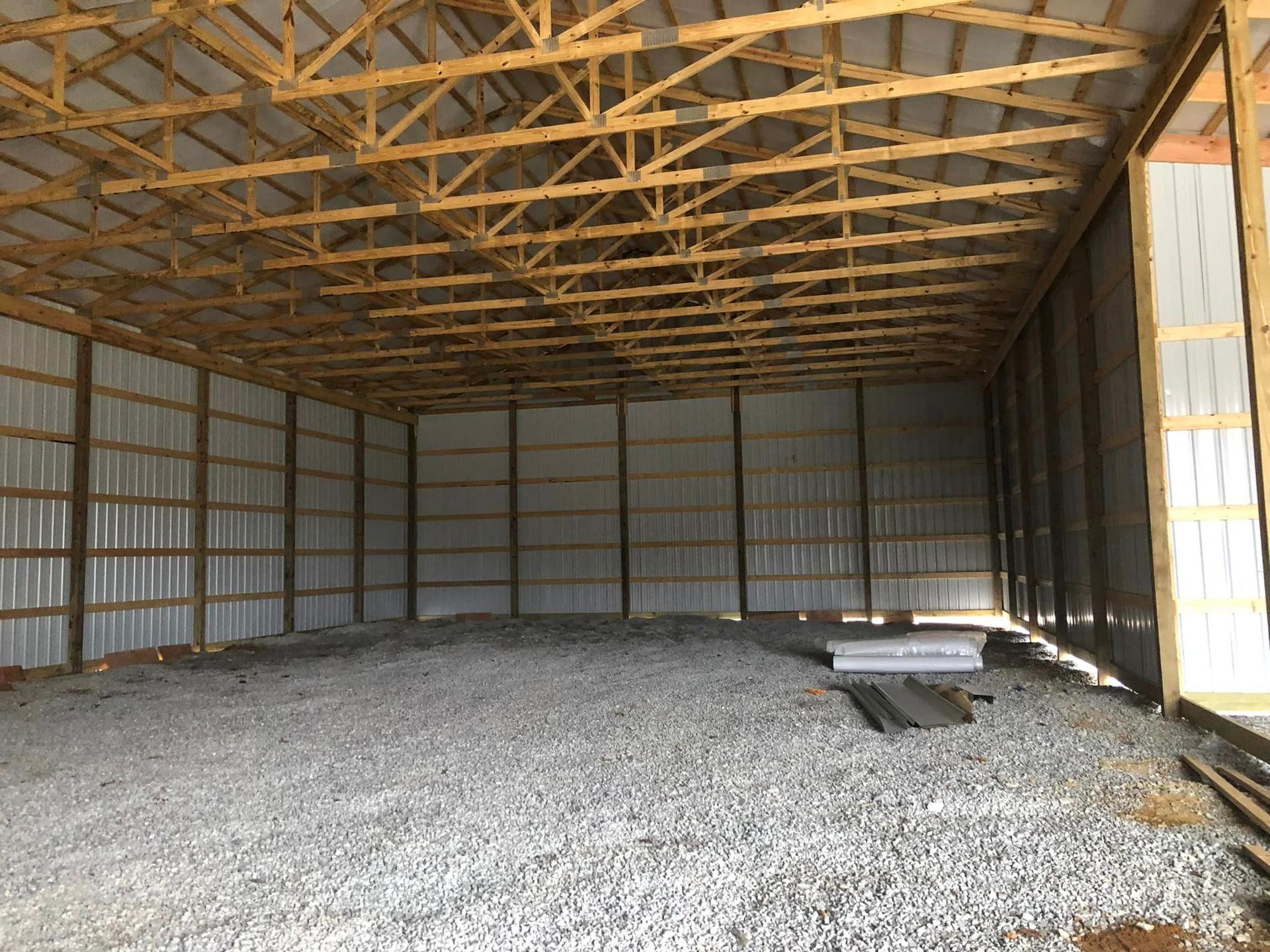 A large empty building with a wooden roof and a gravel floor.