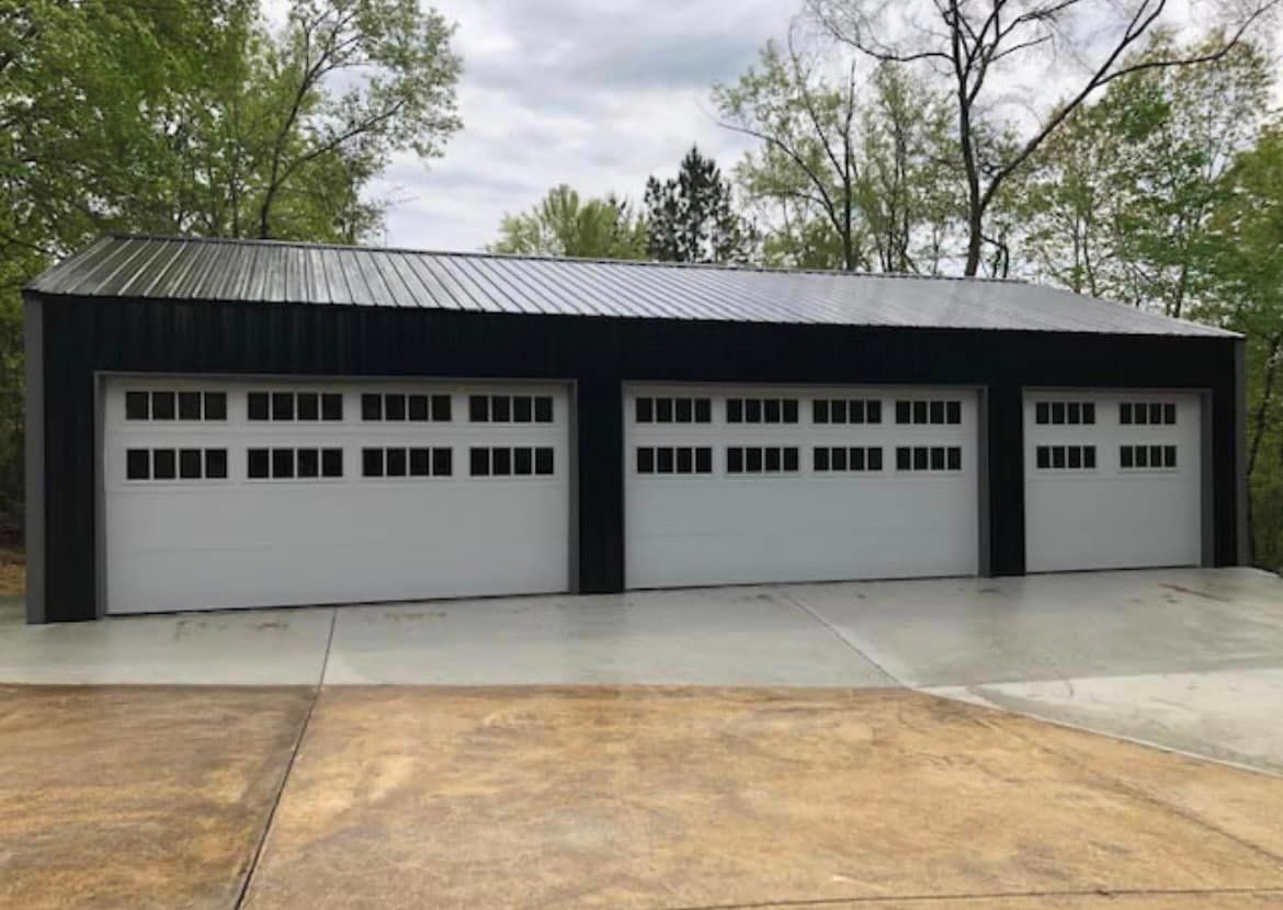 A large garage with three garage doors and a concrete driveway.