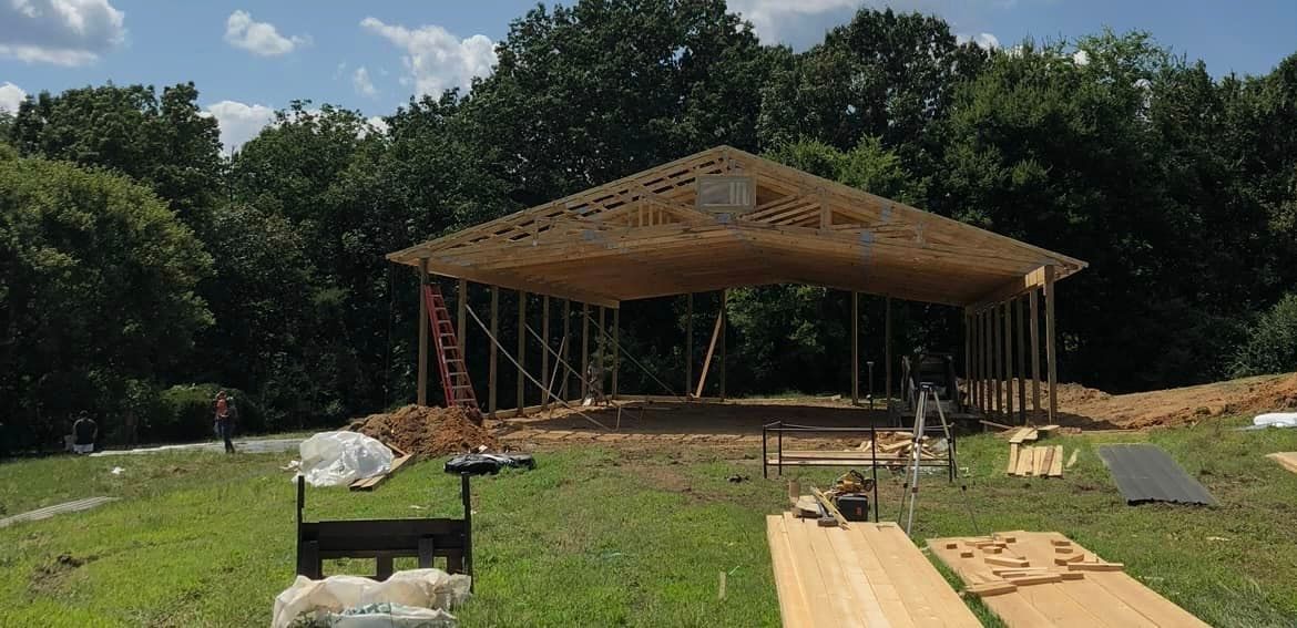 A large wooden structure is being built in a grassy field.