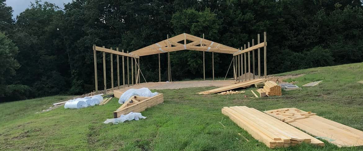 A large wooden structure is being built in a grassy field.