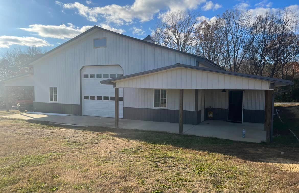 A large white barn with a porch and a garage door.