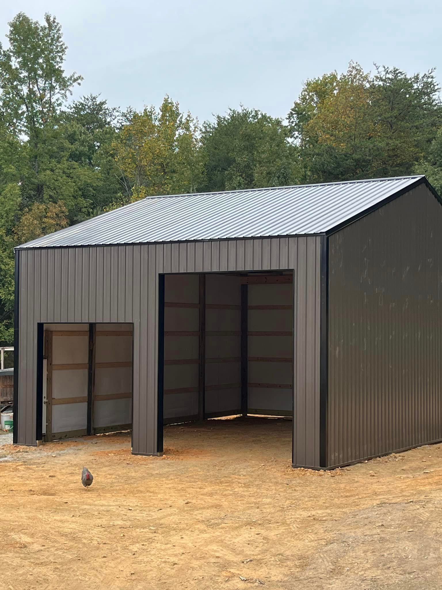 A large metal building is sitting in the middle of a field.