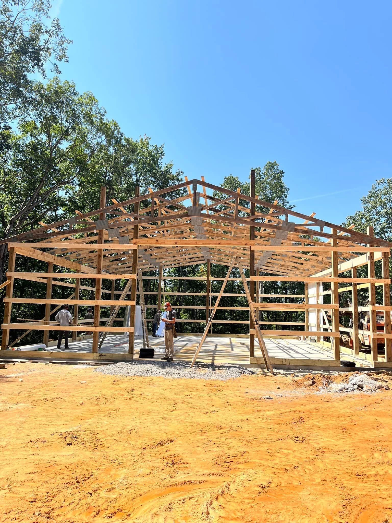 A large wooden structure is being built in a dirt field.