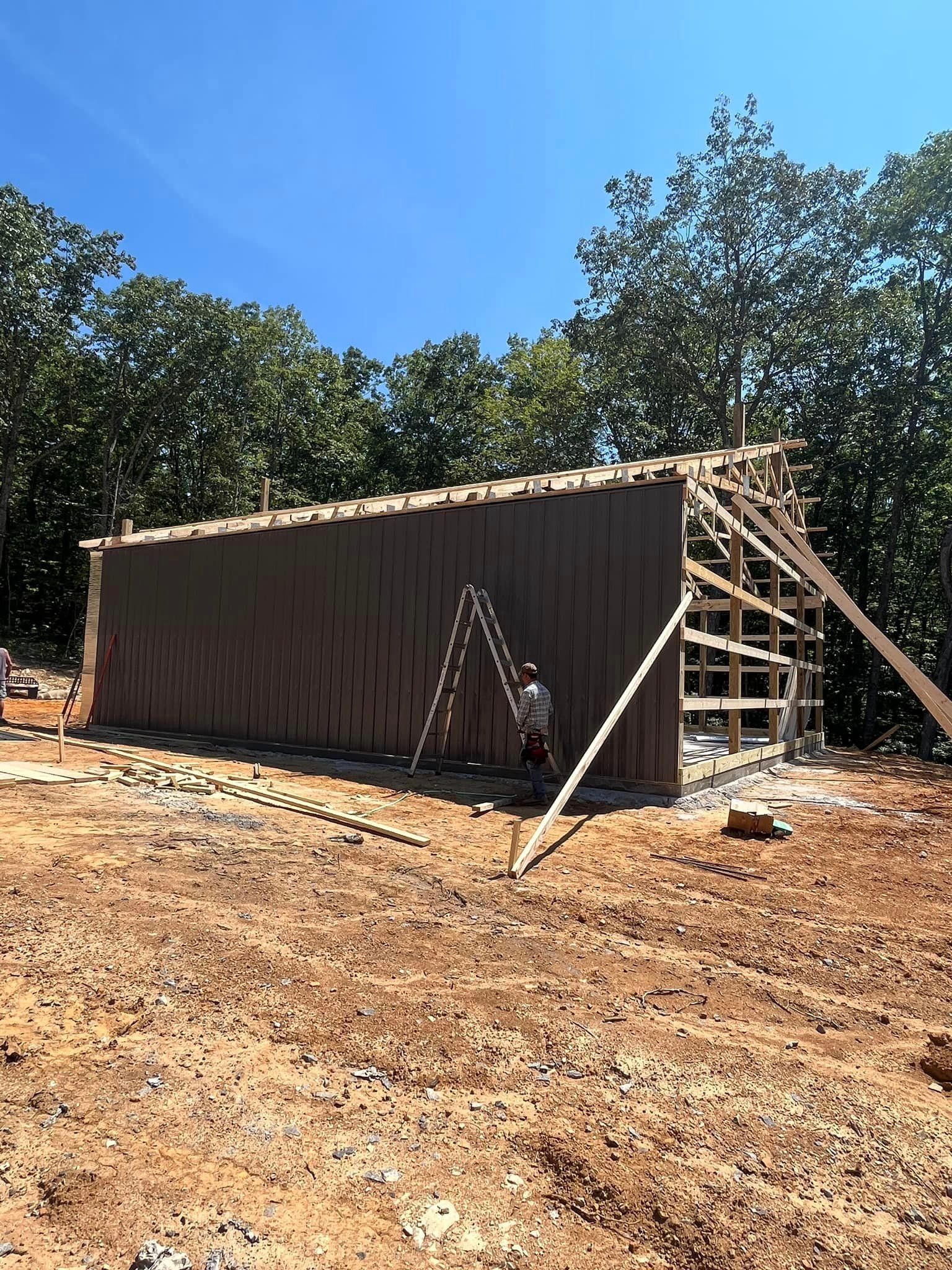 A large wooden building is being built in the middle of a dirt field.