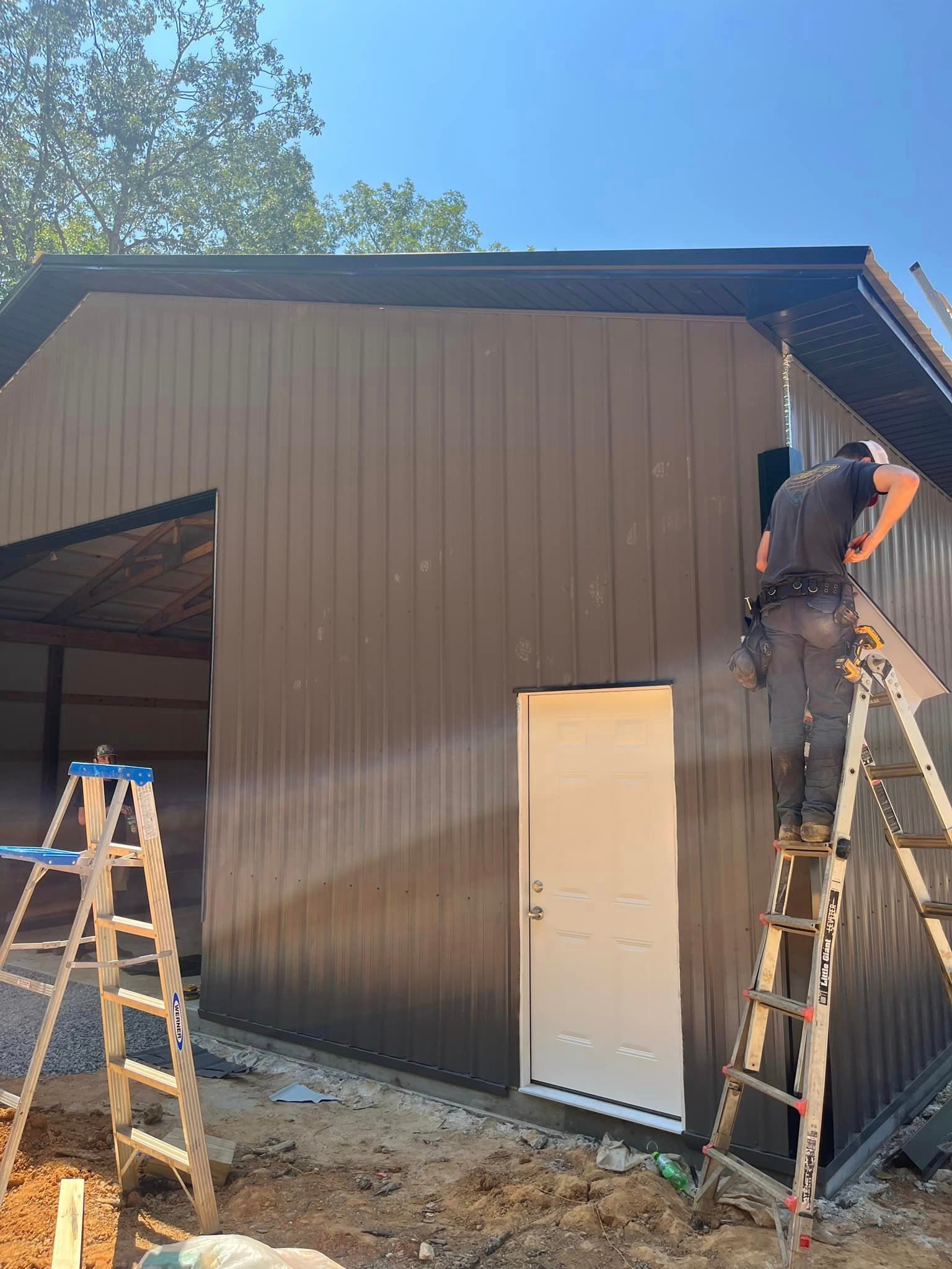 A man is standing on a ladder working on the side of a building.