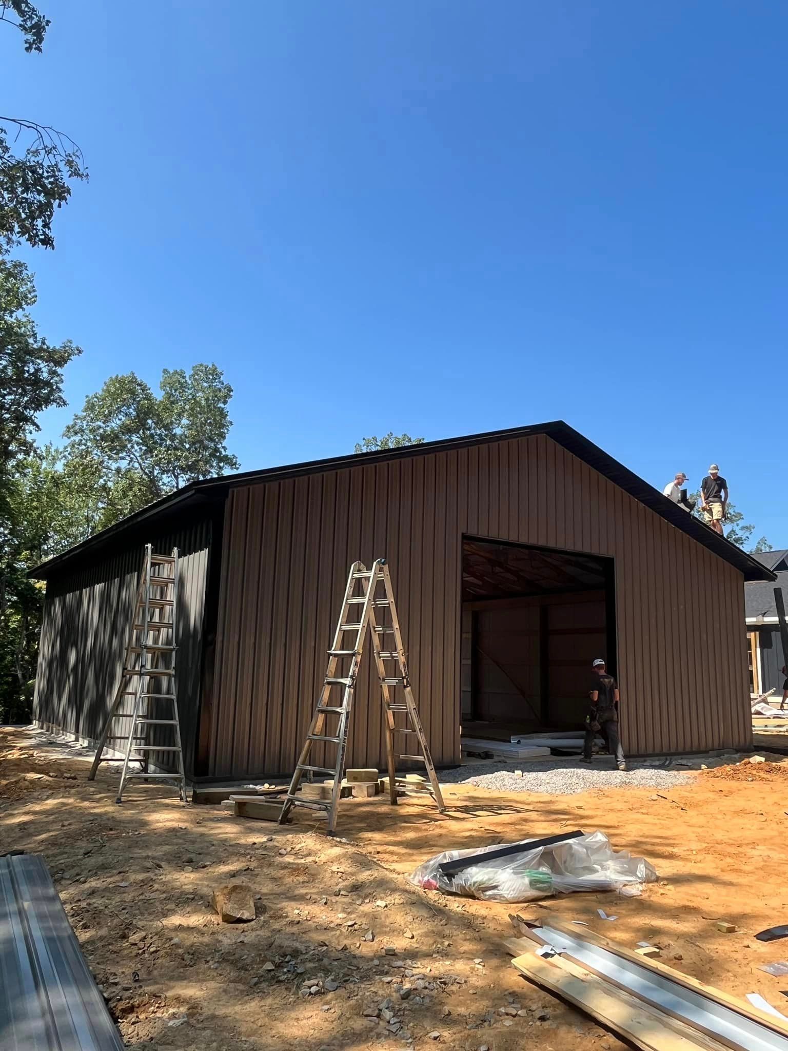 A large barn is being built with a ladder in front of it.