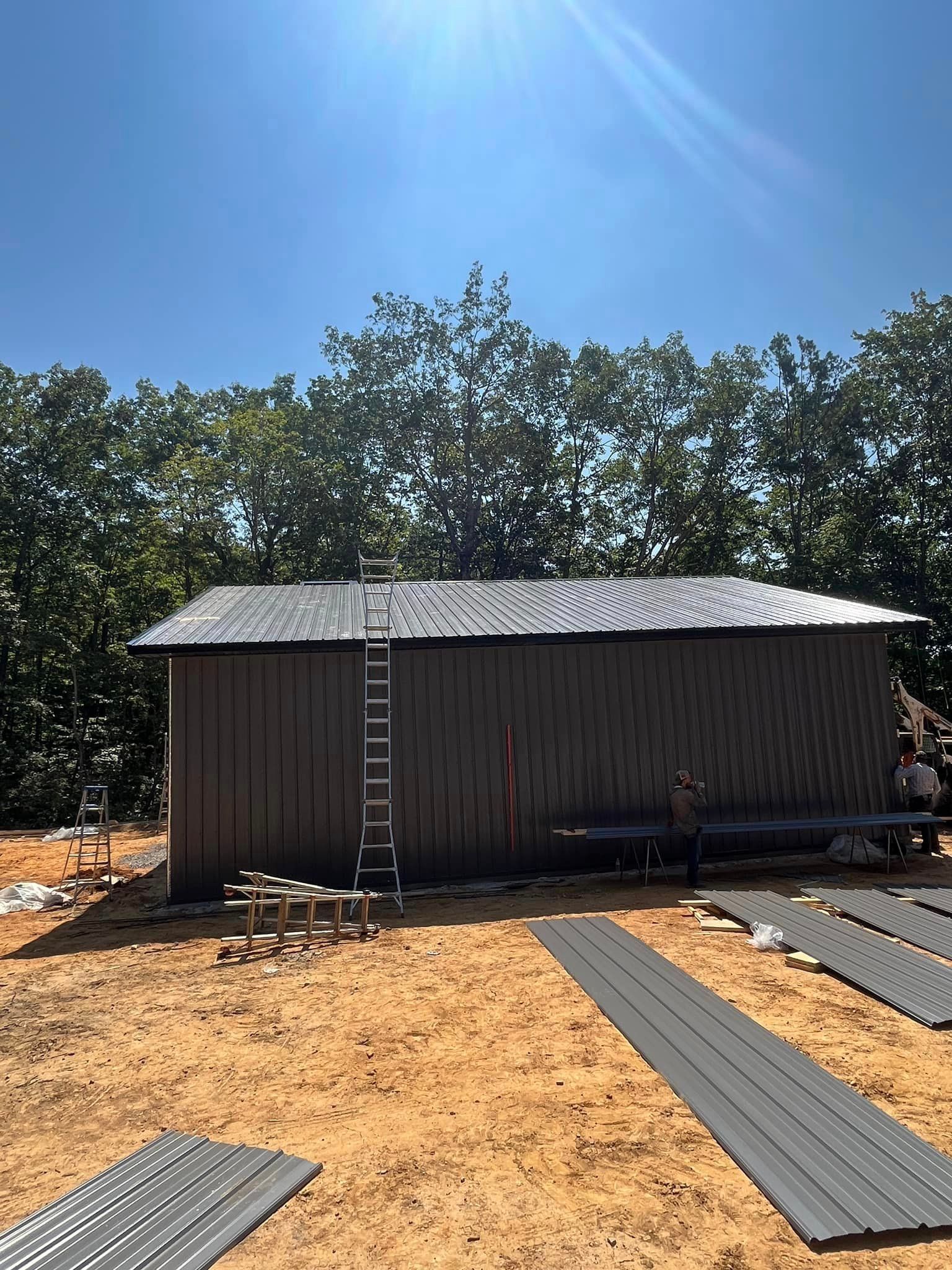 A large metal building is being built in a dirt field.