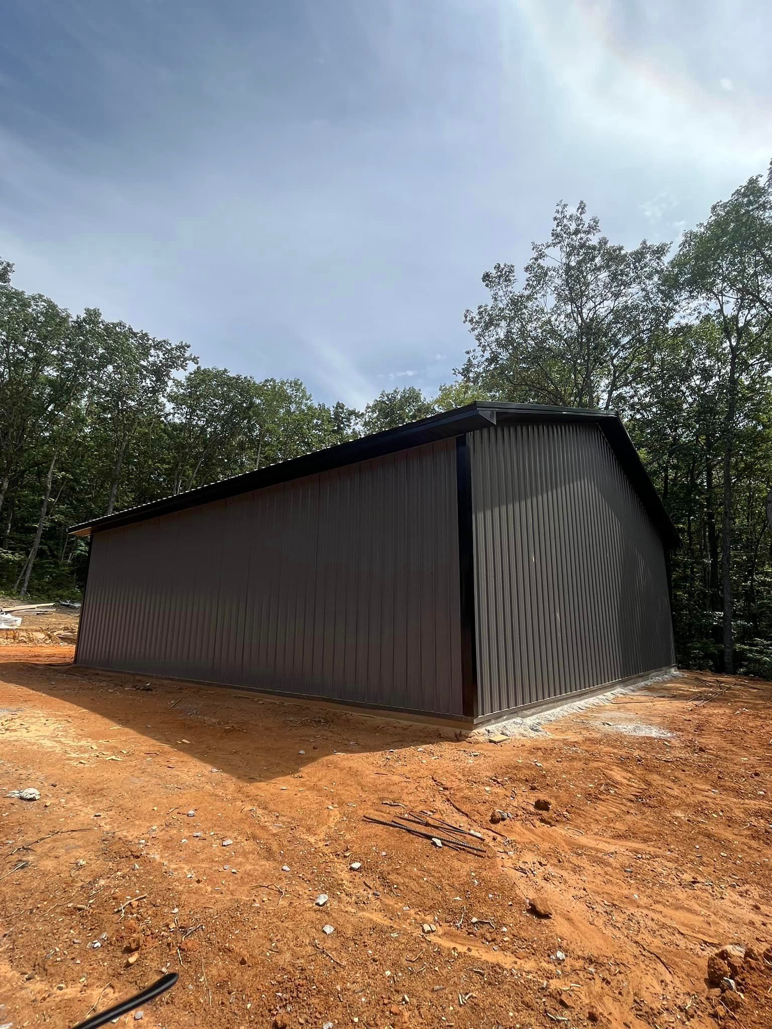 A large metal building is sitting in the middle of a dirt field.