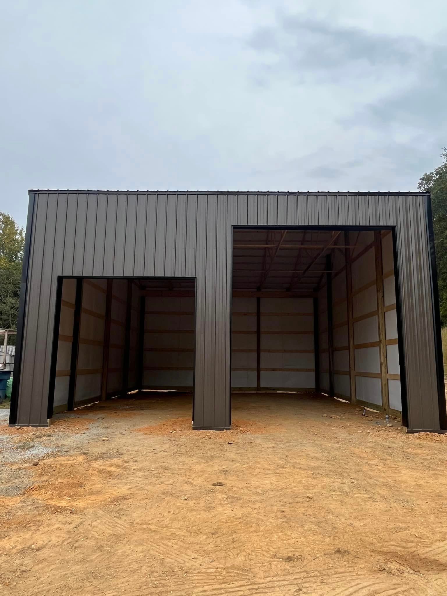 A large metal building is sitting in the middle of a dirt field.