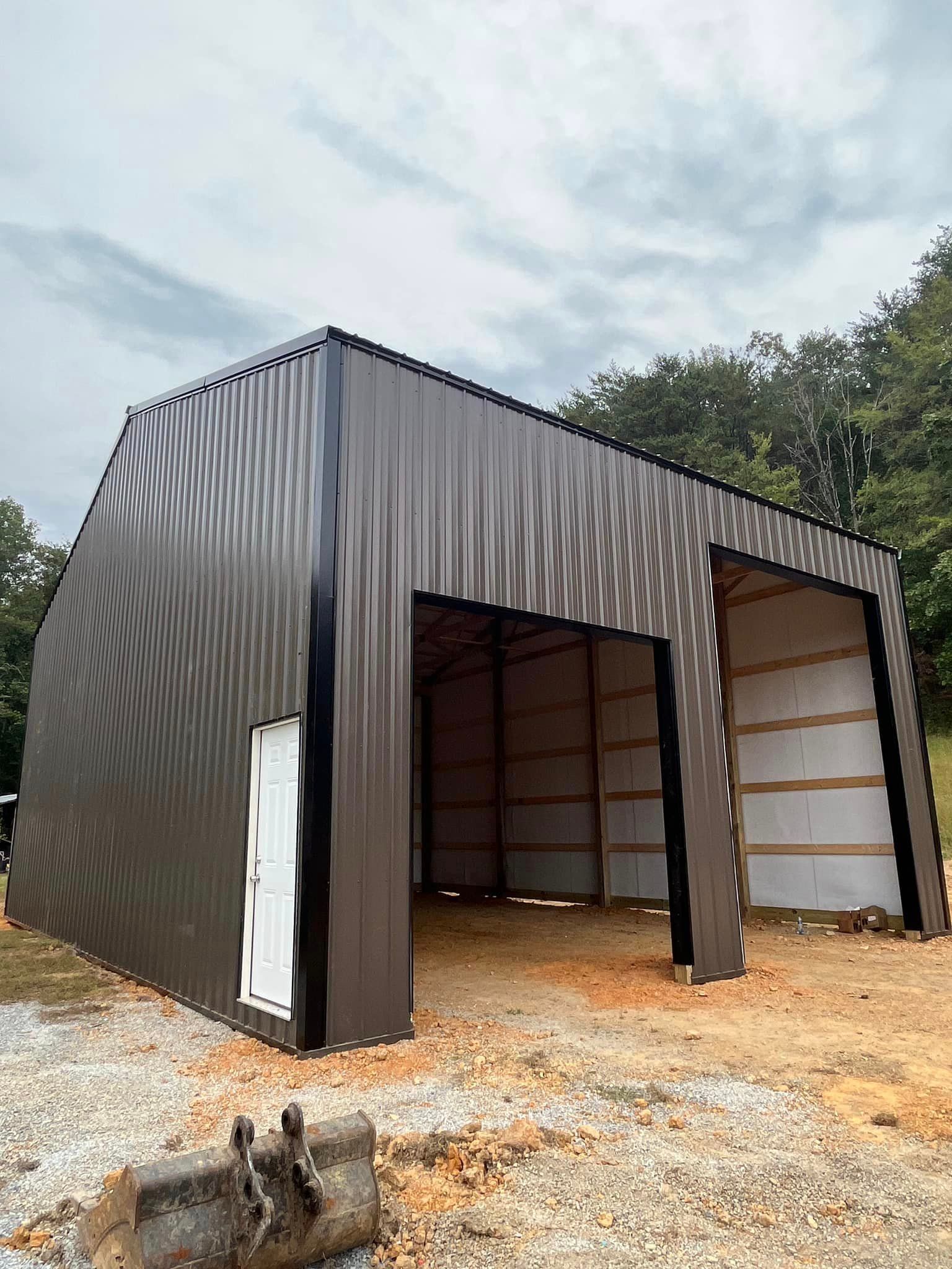 A large metal building is being built in the middle of a dirt field.