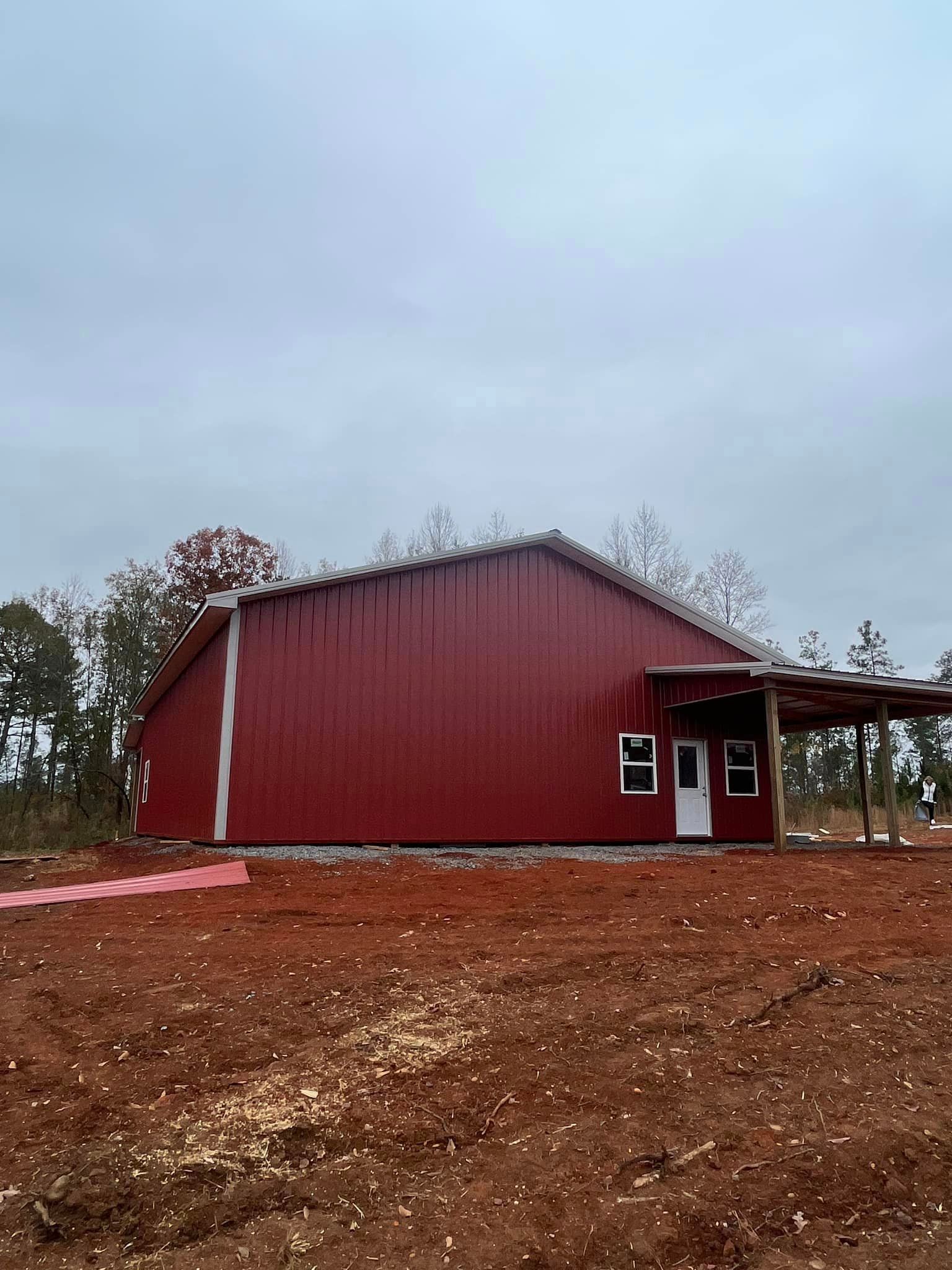 A red barn is sitting in the middle of a dirt field.