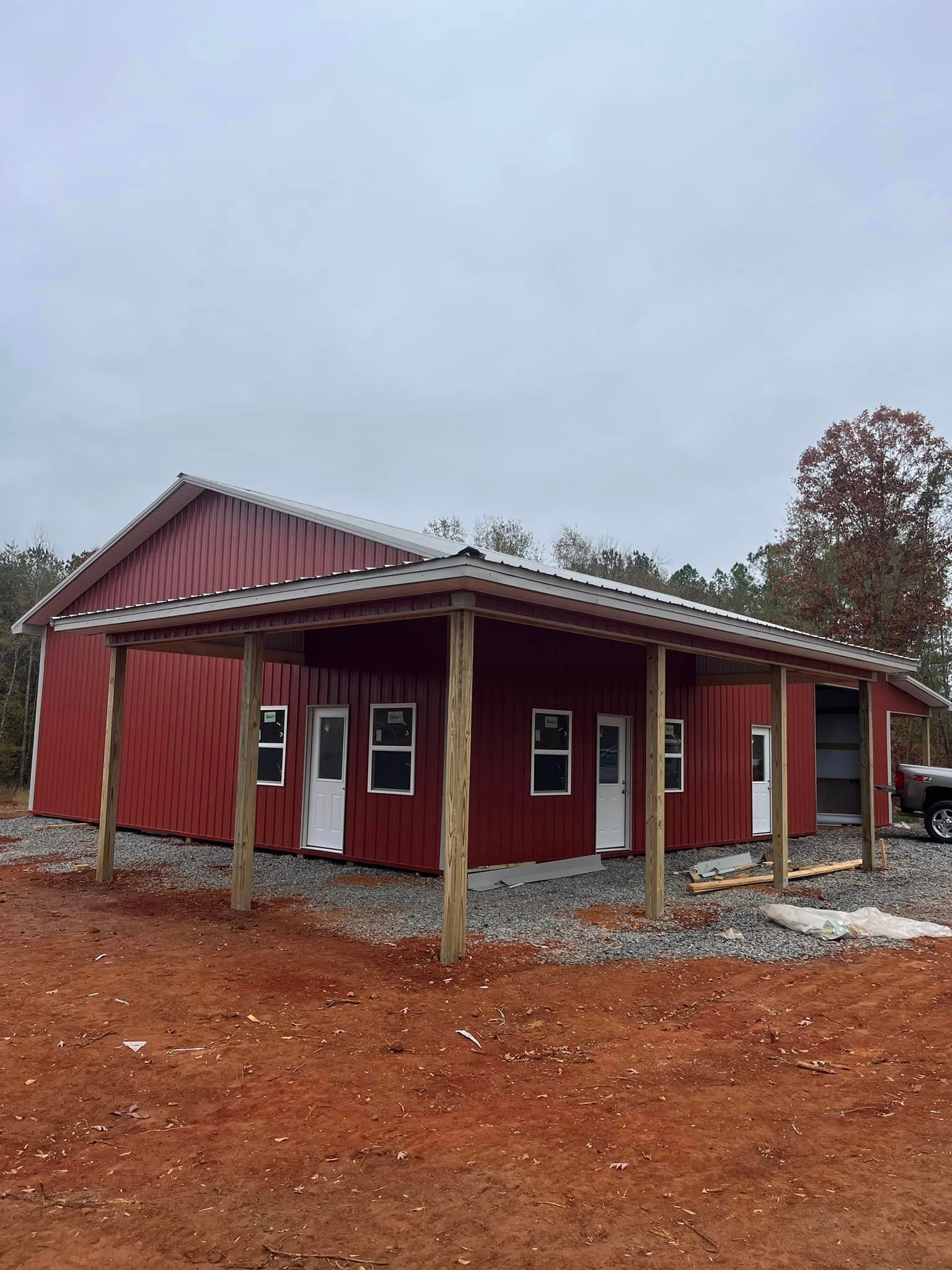 A red barn with a porch and a truck parked in front of it.