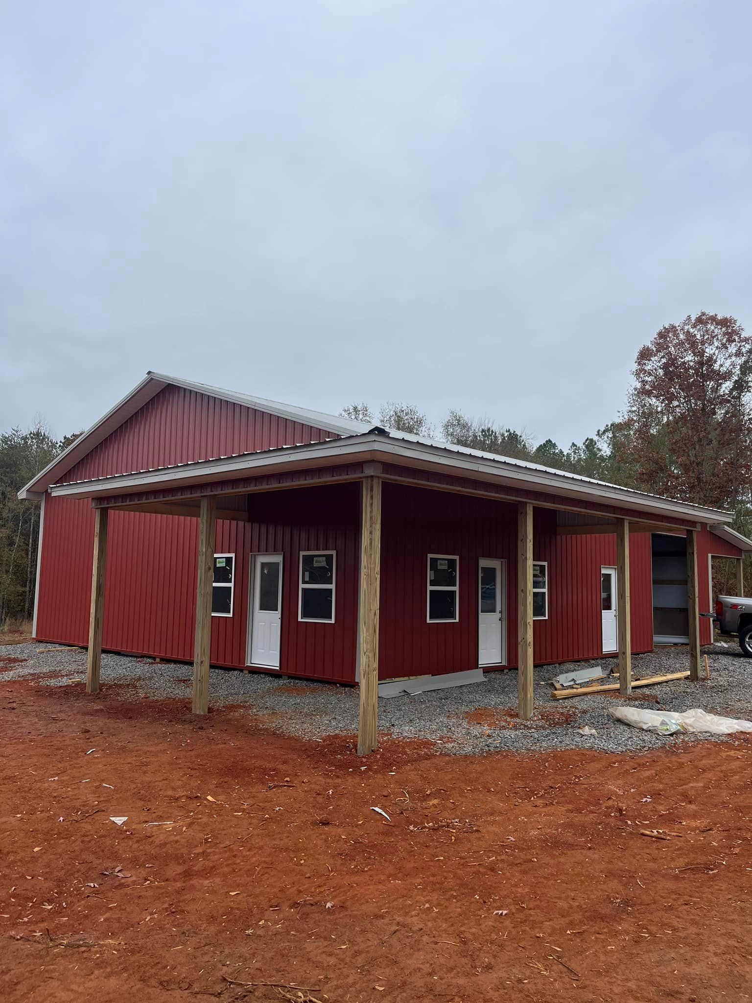 A red barn with a porch and a truck parked in front of it.