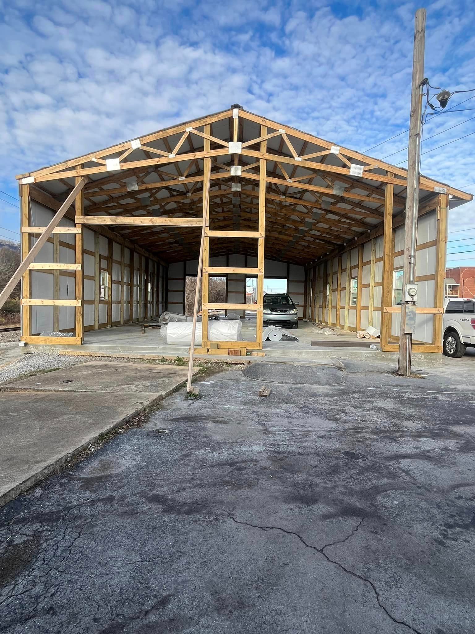 A large wooden building is being built in a parking lot.