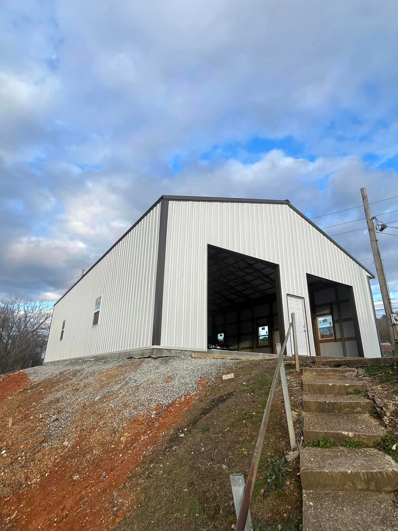 A large white building with stairs leading up to it is sitting on top of a dirt hill.