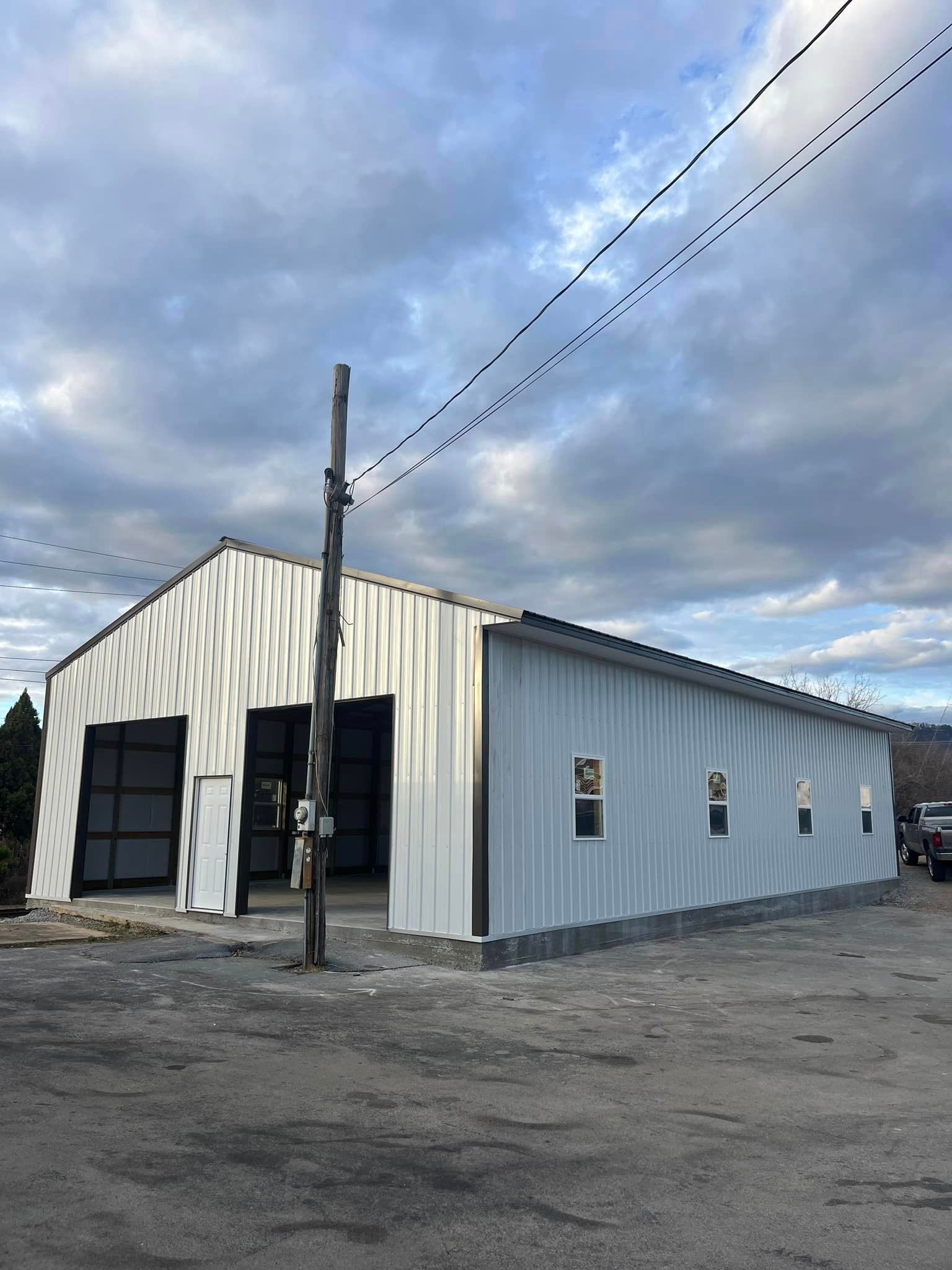 A large white building with a lot of windows is sitting in a parking lot.
